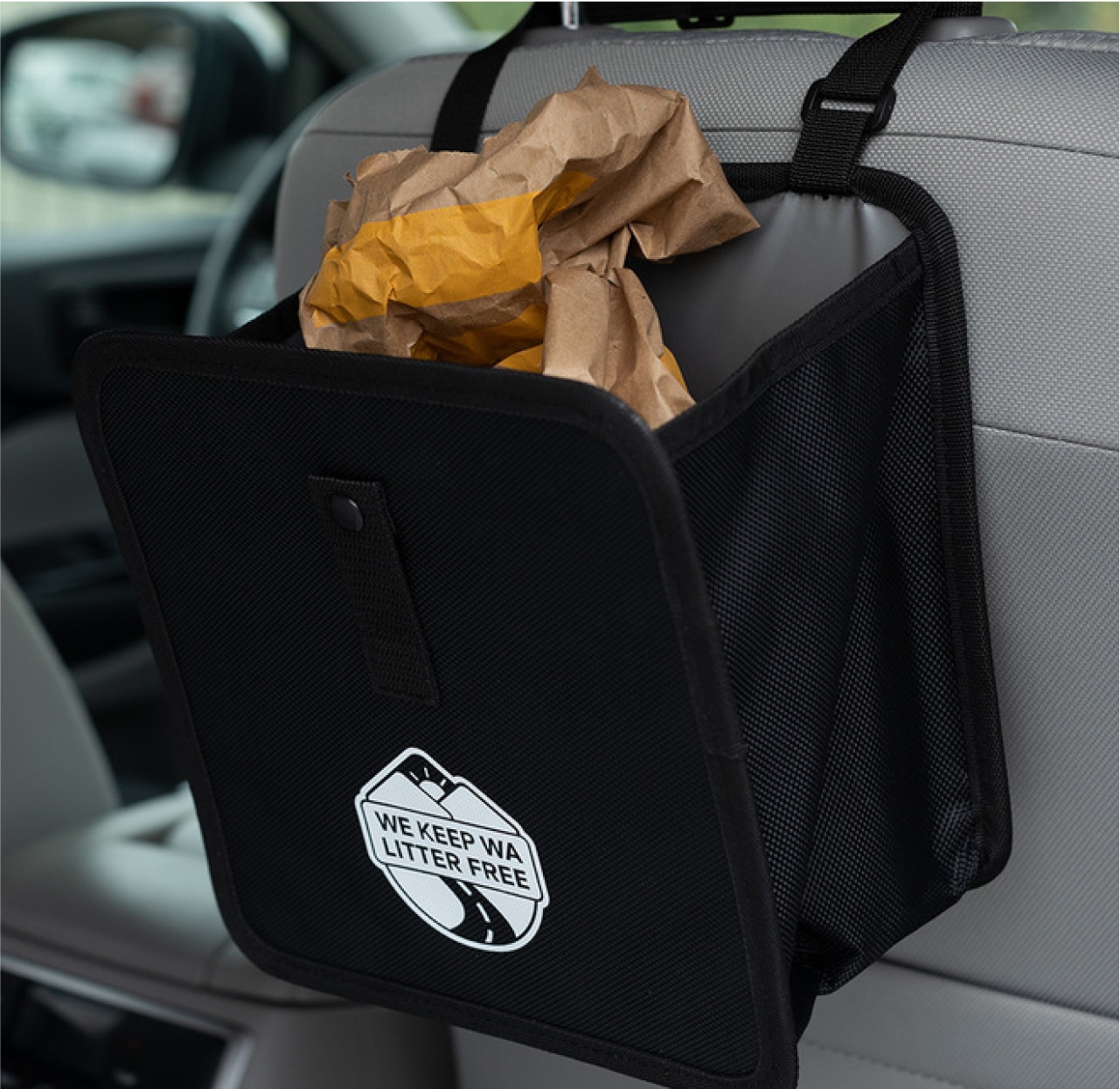 A small bag full of litter in the back of a car seat. 