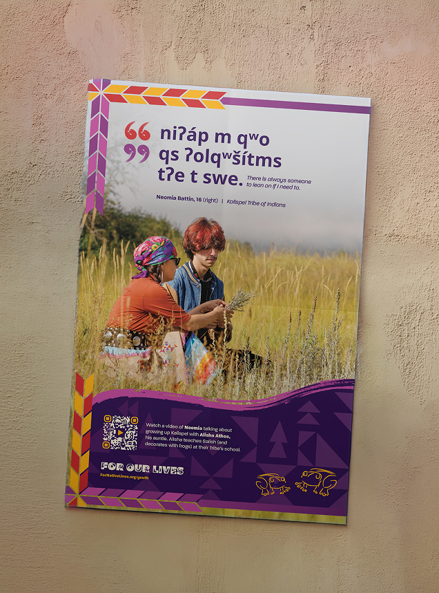 A photo of a poster on a textured wall. The poster features a photo of Neomia Battin and his auntie Alisha Athos sitting together in a grassy meadow. A quote from Neomia appears in Salish with its English translation: 'There is always someone to lean on if I need to.' 